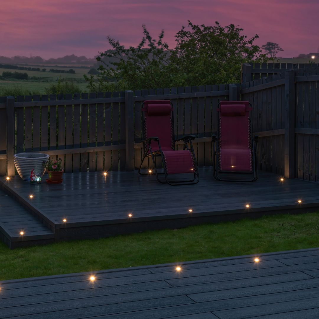 Decking area in residential garden at night with in-deck LED light fixtures