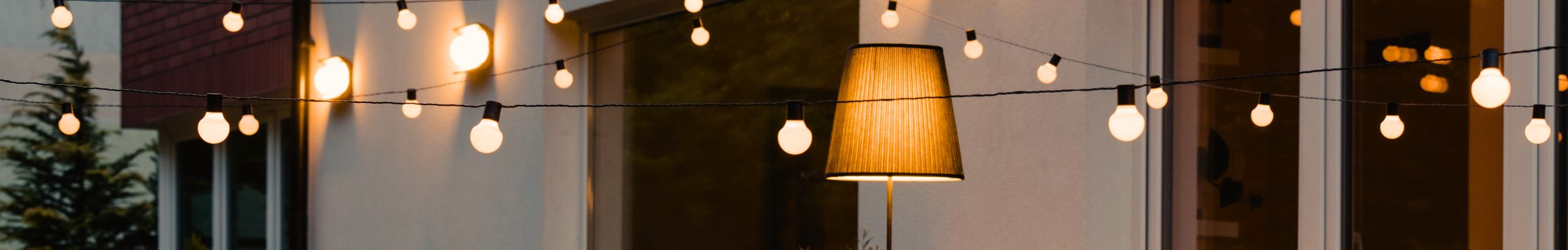 Exterior living space at dusk with warm white lighting - festoons and standing lamp